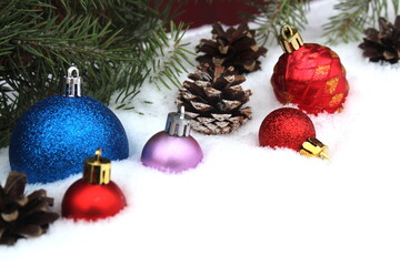 Christmas tree toys, branches and a gift box lie on the snow.