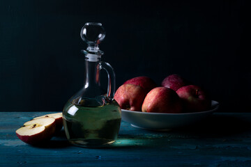 Fresh apples and apple vinegar in bootle on blue wooden background.  Healthy organic food.