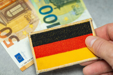 Germany euro money, Germany's financial and economic situation, German flag held in hand against a...