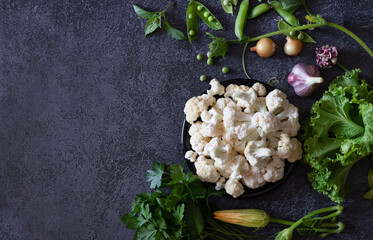 Obraz na płótnie Canvas Cauliflower with vegetables and spices on a dark wood background