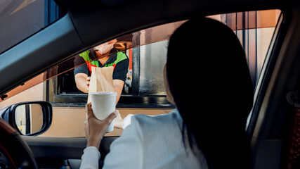 Hand Man in car receiving coffee in drive thru fast food restaurant. Staff serving takeaway order for driver in delivery window. Drive through and takeaway for buy fast food for protect covid19.