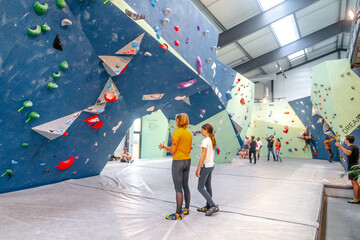 Young girl and her mom climbing on a climbing wall in a gym