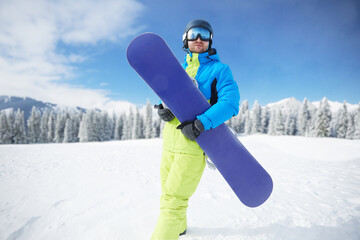 Snowboarder Of Man At Ski Resort On The Background Blue Sky,  Hold Snowboard. Wearing Ski Glasses....
