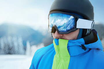 Close up of the ski goggles of a man with the reflection of snowed mountains. A mountain range...