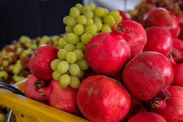 Fresh grapes and pomegranates in crates sold in bulk at a farmers market in San Francisco, California