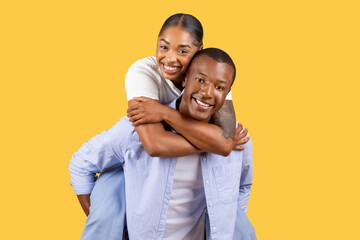 Obraz premium Joyous black couple piggybacking, sharing a laugh