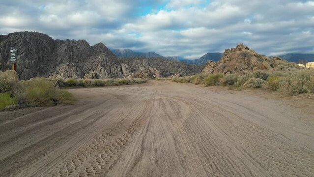 Drone footage of Alabama Hills in California following Movie Road dirt track and then panning upwards to see wider landscape.