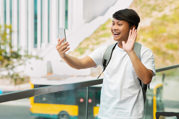 Positive asian guy travel blogger taking selfie by phone - obrazy, fototapety, plakaty