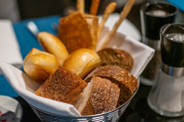 Different types of sliced bread in the basket, on the table in the restaurant