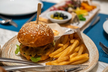 Close up of Burger with Cheese and Vegetable, and French Fries