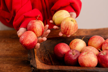 Nutrient-rich display: A woman's hands arrange fresh red apples on a wooden backdrop, embodying the...