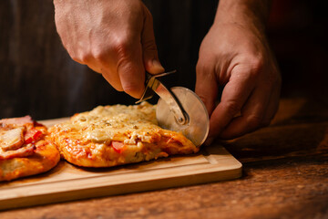 Pizza Cutting Ritual: Engaging in the ritual of pizza cutting, a man skillfully slices a homemade...