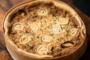 Gourmet Delight: A delectable leek and egg tart, presented on a wooden board, promises a feast for the senses