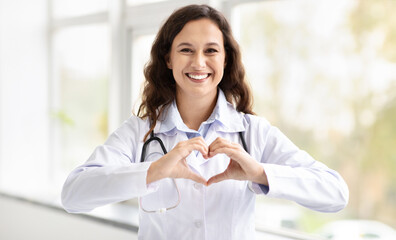Happy millennial woman doctor showing heart shape gesture