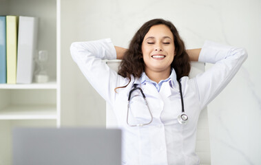 Relaxed woman doctor takes deep breath while working at clinic