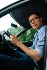 Courier sitting in a car and looking at a digital tablet