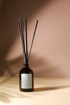 Organic Essential Oil Diffuser Bottle with Wooden Sticks - Elegant Black Design on a Seamless Beige Pink Background, Ready for Custom Labeling