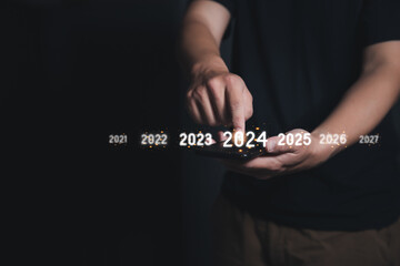 Man Finger pressing on start year 2024 button on smartphone with copy space for text. Concept of...