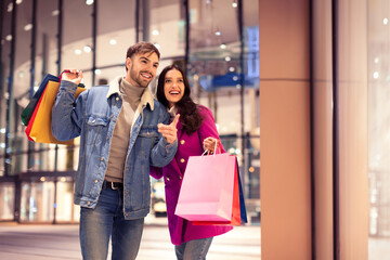 buyers couple with bags outside of modern mall store pointing