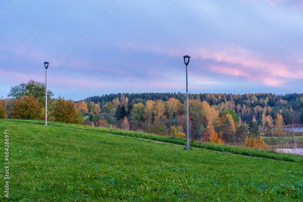 Wall mural two lanterns, a grassy slope and an autumn landscape at sunset