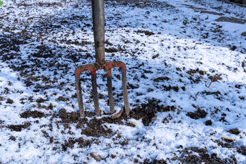 Close-up of a garden digging fork stuck in frosty ground. Preparing the soil for new plants.