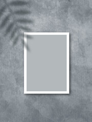 Poster mockup with a white frame and a palm leaf shadow on a gray stone wall background