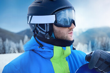 Close up of the ski goggles of a man with the reflection of snowed mountains. A mountain range reflected in the ski mask. Portrait of man at the ski resort on the background of mountains and sky
