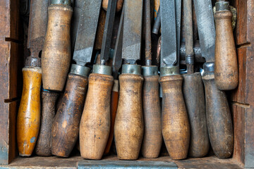Old vintage rasps with wooden handles in wooden tool box . A set of files and rasps for hand...