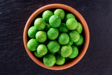 Roasted salted peanuts in a green crispy shell with wasabi flavor, closeup, top view. Food background. Snack to beer