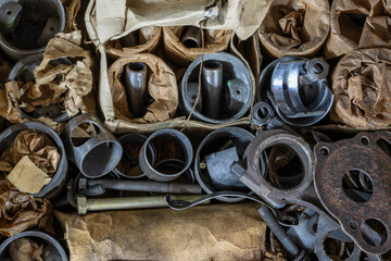 Aluminum pistons of automobile engines in oiled paper for retro cars, closeup, top view. Spare parts for car repair in workshop