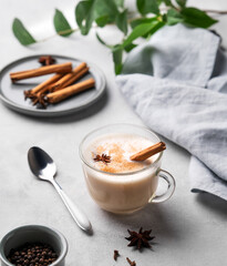 Traditional Indian masala chai latte in a glass cup. Hot drink with milk, spices and herbs on a...