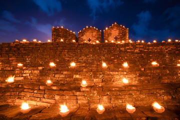 Candles burning at the old wall, Old brick wall decorated with many candles. Light of Lanna Candle...