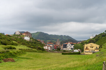 Fototapeta premium Zumaia is a small coastal town in Basque country, Spain. Seen here is a small part of the town and the surrounding hills under a slightly clouded sky