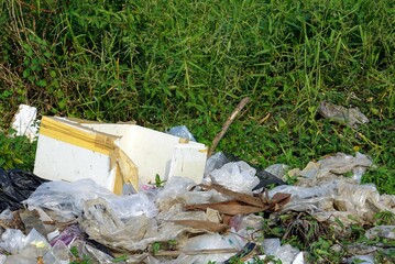 An old white foam box left in the pile garbage area on the ground, pollution and environment...