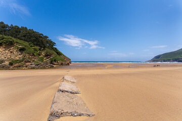 Playa La Arena in Pobeña under a blue sky where the river Barbadun flows into the Bay of Biscay, Basque country, Spain
