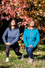 Two mature black women stretching outdoors.