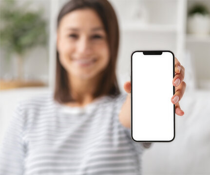 Happy smiling woman showing mobile phone with blank screen standing in room at home