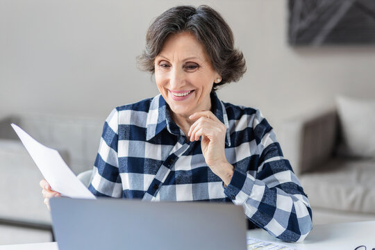 Happy smiling successful senior business woman or entrepreneur working, sitting at her workplace in a modern office