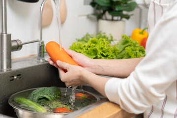Close up asian young woman washing carrot, tomato, broccoli  fresh vegetables, paprika with splash...