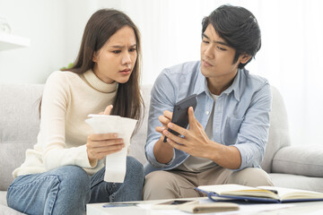 Stressed financial owe asian young couple love hand in holding bills, sitting on sofa together,...