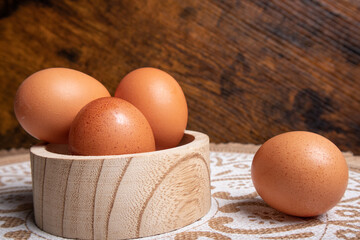 eggs placed on a circular wooden container, one of the eggs is outside, on the table, at the base you can see a mat with mandalas and the bottom is wooden