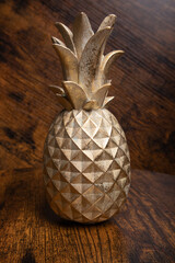 decorative pineapple, close-up of a decorative metal figure in the shape of a pineapple on a wooden background