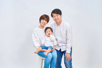 白い背景の前に笑顔で並ぶ家族