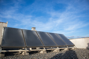 solar panels, five solar panels on the roof of a residential building, in the background you can see the blue sky and some clouds