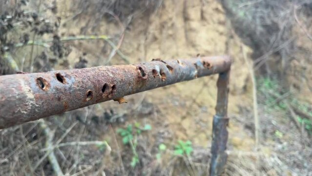 punctured rusty pipe structures with bullet holes on a training ground on a gray autumn day
