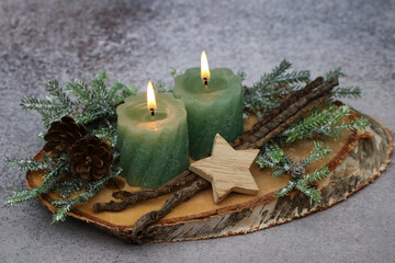Weihnachts und Adventsdekoration, Kerzen und Zweige auf einer Baumscheibe arrangiert. 