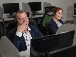 Two call center employees. A bored man and a friendly woman talking on a headset to clients. 