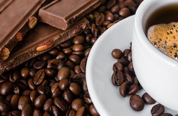 Close-up of chocolate on coffee beans,white cup of coffee out of focus