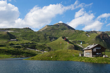 lake in the mountains of austria with a small cabin at the  großglockner hochalpenstraße