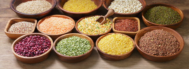 bowls of legumes, lentils, chickpeas, rice and beans on wooden background